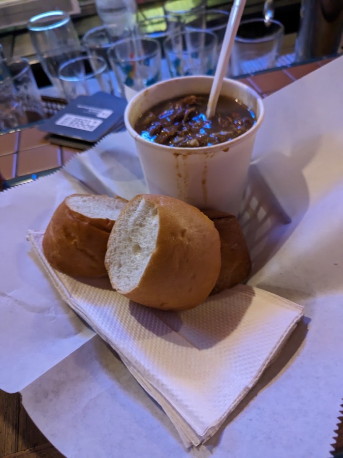 A cup of chicken and andouille gumbo with a bread roll